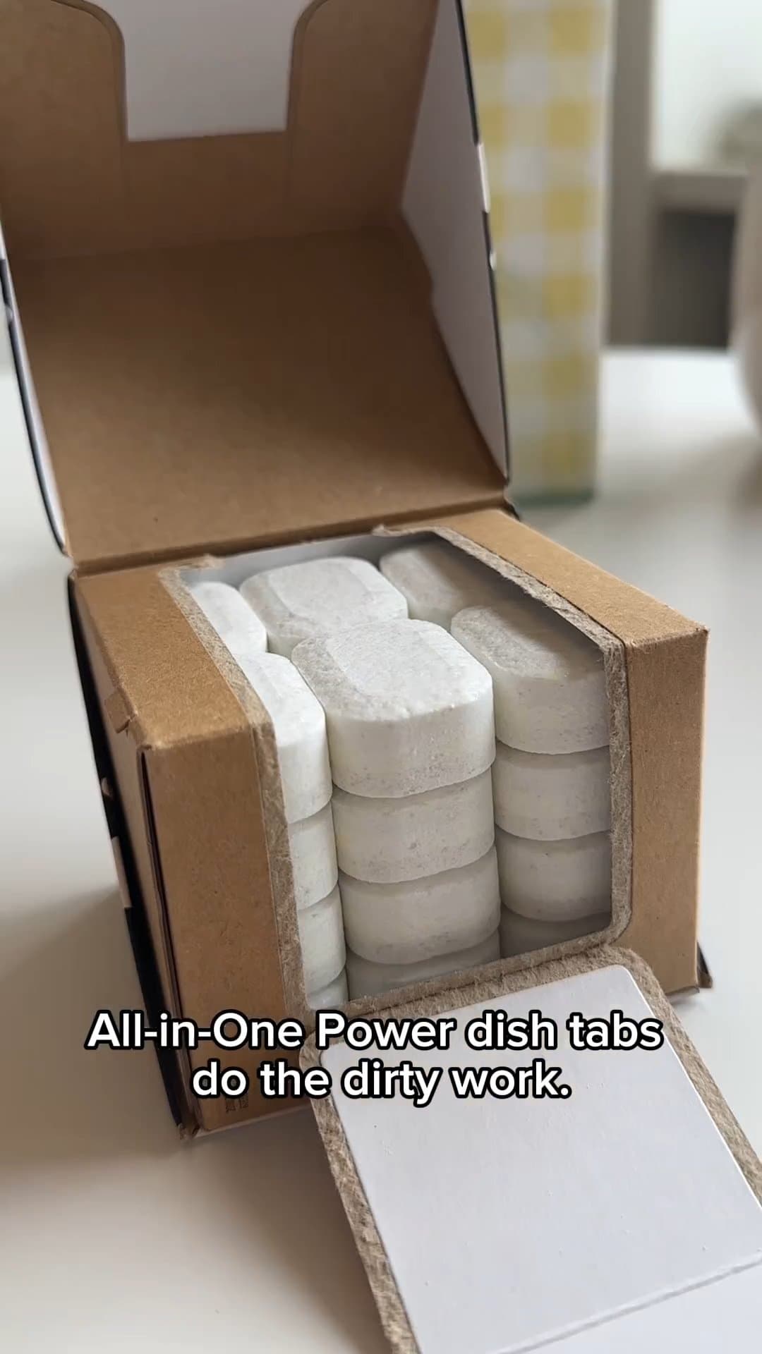 Open box of white dishwashing tablets with text overlay: "All-in-One Power dish tabs do the dirty work."